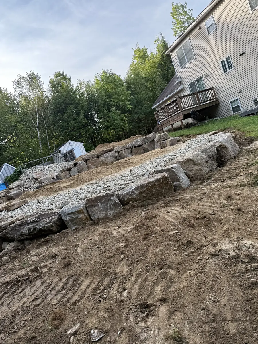 Long granite retaining wall stepped up a regraded slope