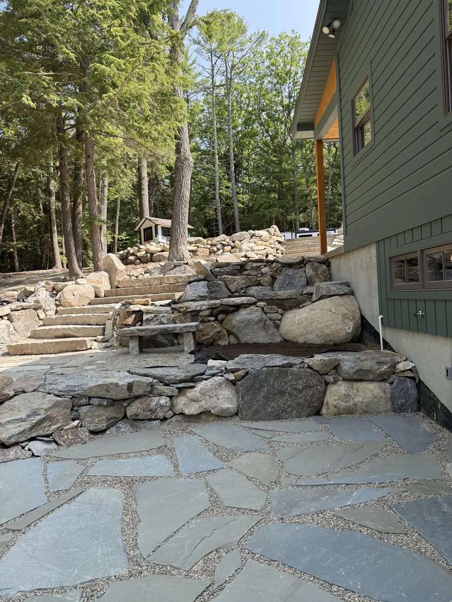 Granite steps and fieldstone walls framing a flagstone patio